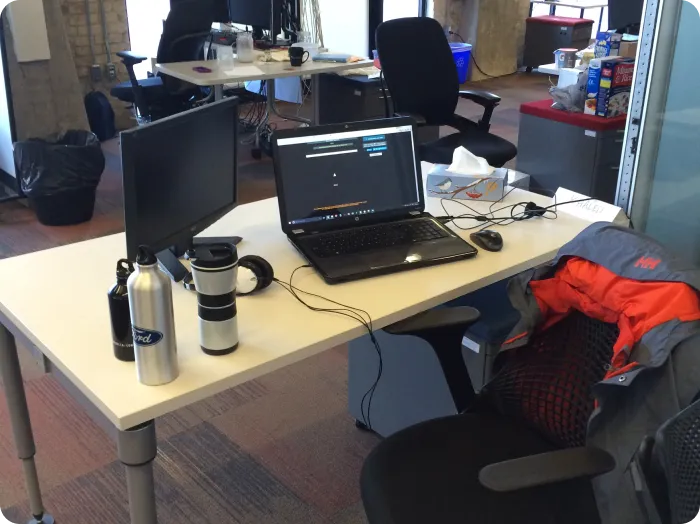 Engineer's desk setup with laptop, monitor, and LabsCubed branded water bottles.