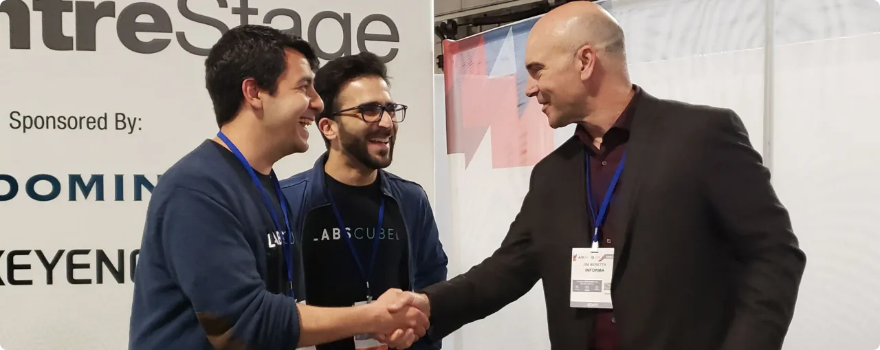 LabsCubed team members shaking hands and networking at an industry event.