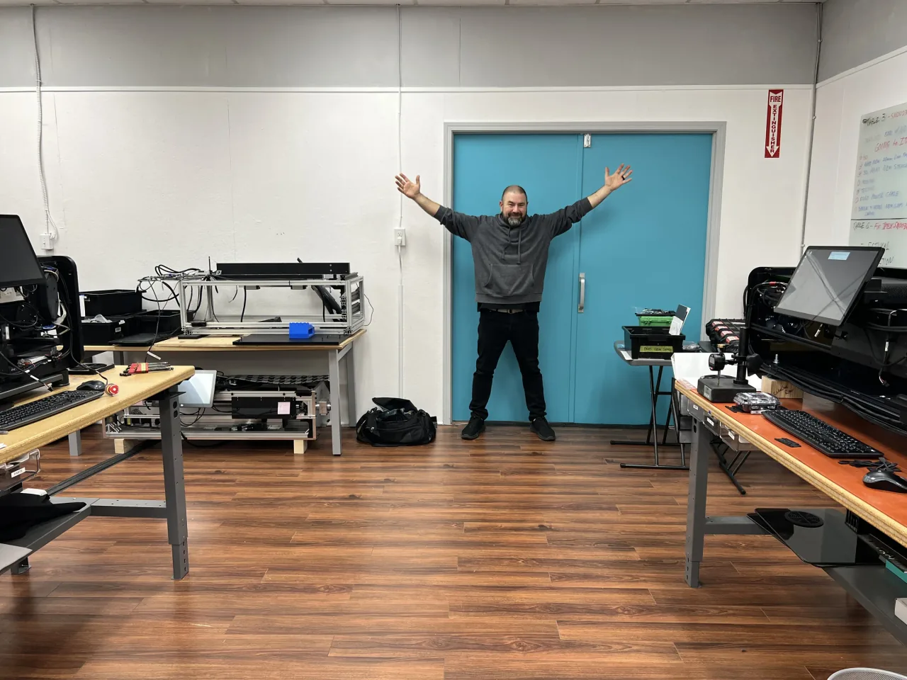 A LabsCubed team member with arms spread wide in the open workshop of the larger LabsCubed facility.